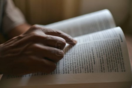 Foto de Primer plano en las manos de una persona irreconocible leyendo la Biblia y orando. - Imagen libre de derechos