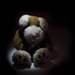 Stuffed animal illuminated by spotlight in a dark room. Child abuse and violence concept. Sad dramatic mood for negative themes such as bullying at school, child abuse, pedophilia, traumatic childhood or kidnap.