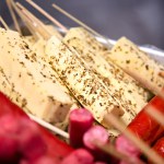 Curd cheese skewers seasoned with herbs and sausages on a counter. Street food