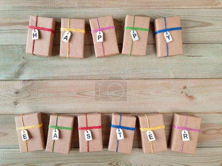 Photo for Easter gift boxes. Copyspace. Top view. Template for card, advertising, events, discount. Boxes wrapped in craft paper with labels saying Happy Easter lie on wooden table. Space for text. Flat lay. - Royalty Free Image