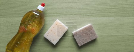 Photo for Eco-friendly products for kitchen. Copyspace. Top view. Bottle of detergent with transparent image of berries and washcloth made of natural materials on green wooden table. Flatlay. Place for text. - Royalty Free Image