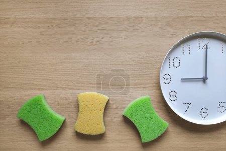 Photo for Timetable and schedule housework concept. Flat lay. Place for text. Kitchen cleaning sponge and clock on wooden table background. Deep clean time. 9 am. Copy space. Top view. Tips for house cleaning. - Royalty Free Image