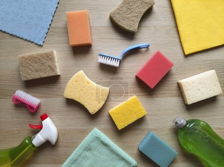 Photo for Background with cleaning tools in kitchen, in house. Flat lay. Kitchen sponges, washclothes, scrub-brushes, detergent liquid, cleaning spray lie on wooden table. Hygiene concept. Top view. - Royalty Free Image