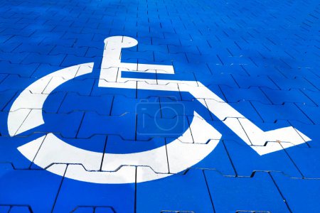 Photo for White symbol of a wheelchair on blue pavement tiles. City accessibility for people with disabilities. Accessible parking concept. Vacant parking spot. - Royalty Free Image
