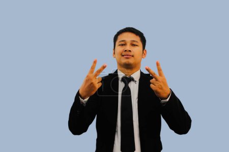 Adulto asiático hombre sonriendo a la cámara y haciendo dos dedos signo