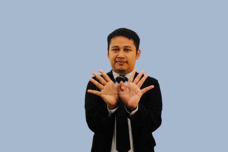 Photo for Adult Asian man smiling at the camera and doing pigeon fingers sign - Royalty Free Image