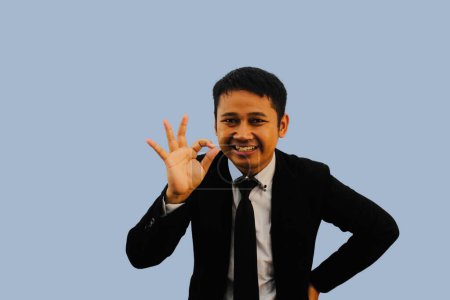 Erwachsener asiatischer Mann lächelt freundlich, während er OK Fingerzeichen gibt