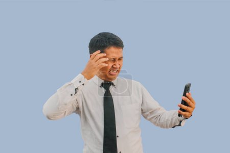 Adulto asiático hombre impactado cara mientras que mirando a teléfono móvil