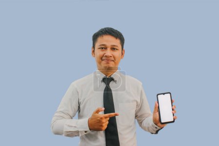Adult Asian man smiling confident while pointing to empty handphone screen that he hold
