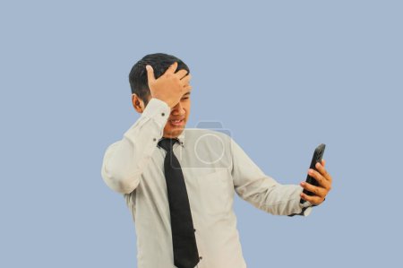 Adulto asiático hombre impactado cara mientras que mirando a teléfono móvil