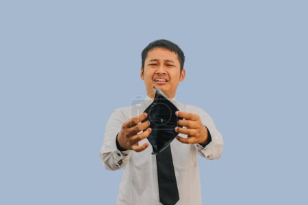 Adult Asian man showing empty wallet with shocked and sad face expression