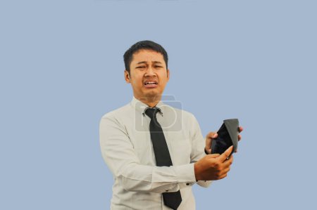 Adult Asian man showing his empty wallet with worried and sad expression