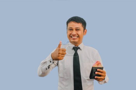 Adult Asian man smiling while holding wallet with money and give thumb finger sign