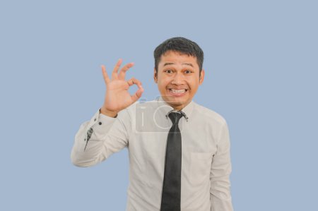 Erwachsener asiatischer Mann lächelt freundlich und gibt mit den Fingern "OK" -Zeichen