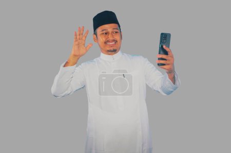 Hombre asiático musulmán mostrando expresión de cara emocionada durante una videollamada con su familia durante la celebración del Ramadán