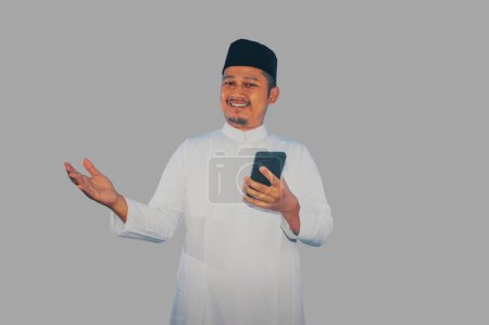 Moslem Asian man smiling happy when holding a mobile phone