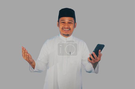Photo for Moslem Asian man smiling happy when holding a mobile phone - Royalty Free Image