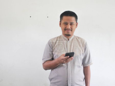 Adulte asiatique homme portant tenue décontractée souriant tout en regardant le téléphone mobile