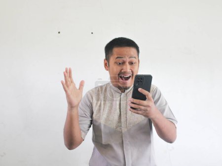 Photo for Adult Asian man looking to his mobile phone with wow expression - Royalty Free Image