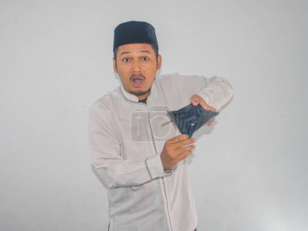 Asian muslim man showing empty wallet with shocked face expression