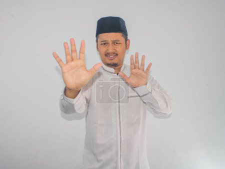 Moslem Asian man give stop hand sign with serious expression