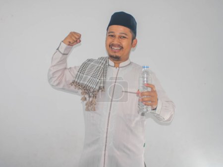 Hombre musulmán mostrando su músculo bíceps mientras sostiene una botella de plástico para beber