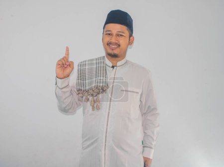Moslem Asian man smiling at the camera and showing one finger sign