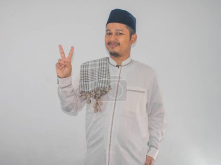 musulmán asiático hombre sonriendo a la cámara y mostrando dos dedos