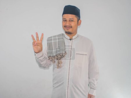 musulmán asiático hombre sonriendo a la cámara y mostrando tres dedos signo