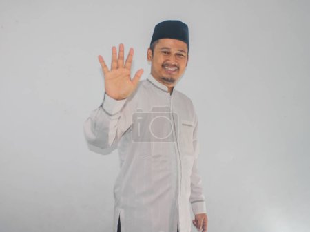 Musulman asiatique homme montrant expression heureuse en agitant la main pour saluer quelqu'un