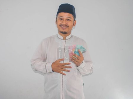 Téléchargez les photos : Asiatique musulman homme tenant de l'argent avec geste reconnaissant - en image libre de droit