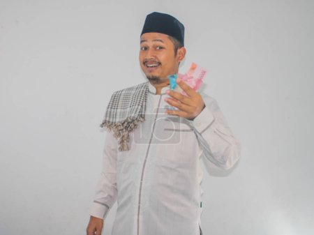 Téléchargez les photos : Asiatique musulman homme souriant heureux tout en montrant de papier-monnaie - en image libre de droit