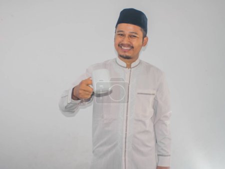 Moslem Asian man smiling at the camera while holding a drinking glass