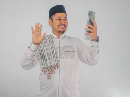 Hombre asiático musulmán mostrando expresión de cara emocionada durante una videollamada con su familia durante la celebración del Ramadán