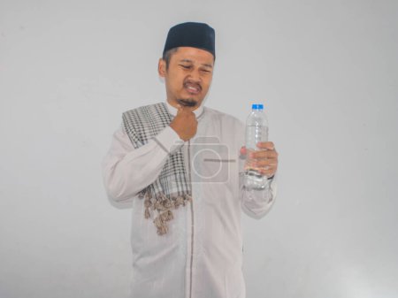 Moslem Asian man showing relieved expression after drink a water