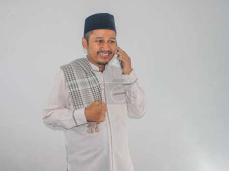 Moslem asiatischer Mann lächelt glücklich, während er einen Anruf entgegennimmt