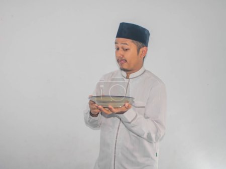 Moslem asiatischer Mann lächelt glücklich, während er einen leeren Teller hält