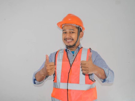 A man wearing construction hardhat smiling and give two thumbs up