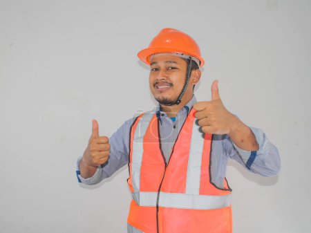 A man wearing construction hardhat smiling and give two thumbs up
