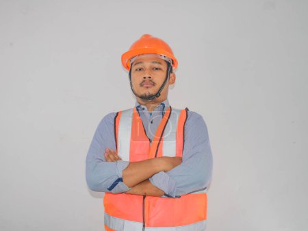 Asiatischer Bauarbeiter mit Warnweste steht mit selbstbewusster Geste schief am Arm
