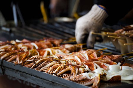  fresh squids is being grilled to a golden perfection on the barbecue grill