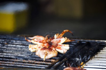  fresh squids is being grilled to a golden perfection on the barbecue grill