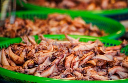 grüne Körbe sind mit frischen Tintenfischen gefüllt, die einen reichen Meeresgeschmack präsentieren