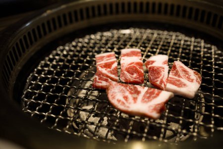  slices of beef being grilled over a charcoal fire