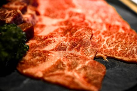 meticulously cut and well-arranged beef with premium marbling alongside fresh green herbs