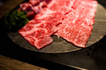 Photo for Meticulously cut and well-arranged beef with premium marbling alongside fresh green herbs - Royalty Free Image