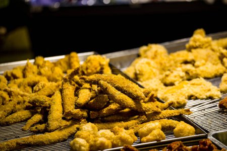  une gamme d'aliments frits dorés et croustillants, y compris le poulet, les crevettes et divers autres articles disposés sur un support métallique