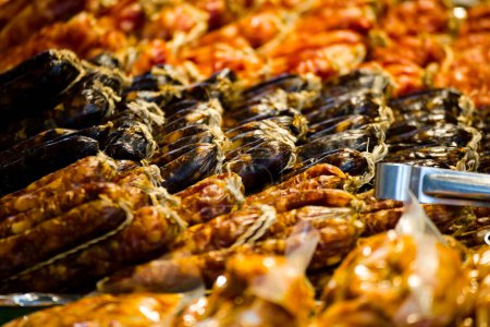 a close-up of Chinese-style sausages hung in an orderly fashion at a market stall