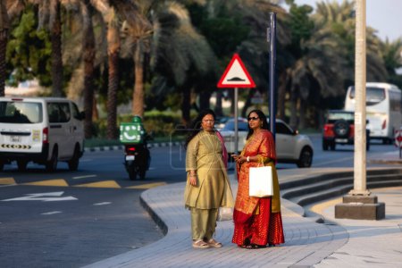 Photo for Dubai, UAE - January 20221: Two Indian women wearing colorful saris waiting for taxi in street in Dubai. High quality photo - Royalty Free Image