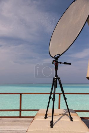 Photo for Working with a solar reflector for photography on a tripod on the terrace of a luxury room in the Maldives. Photo reflector. High quality photo - Royalty Free Image